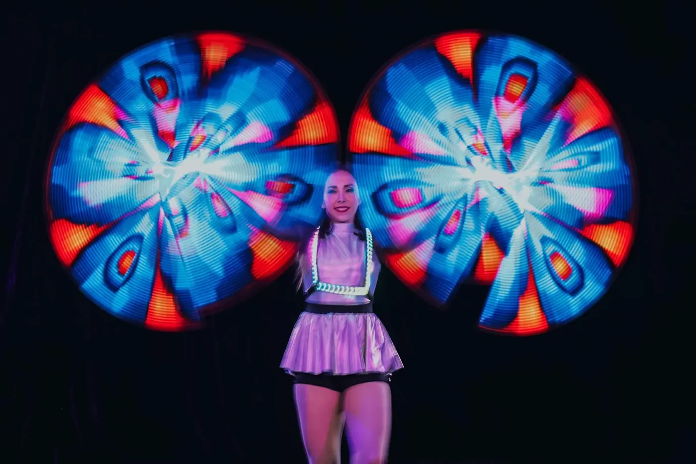 Sarah M Moser performing with two spinning circles of blue, red and white light.