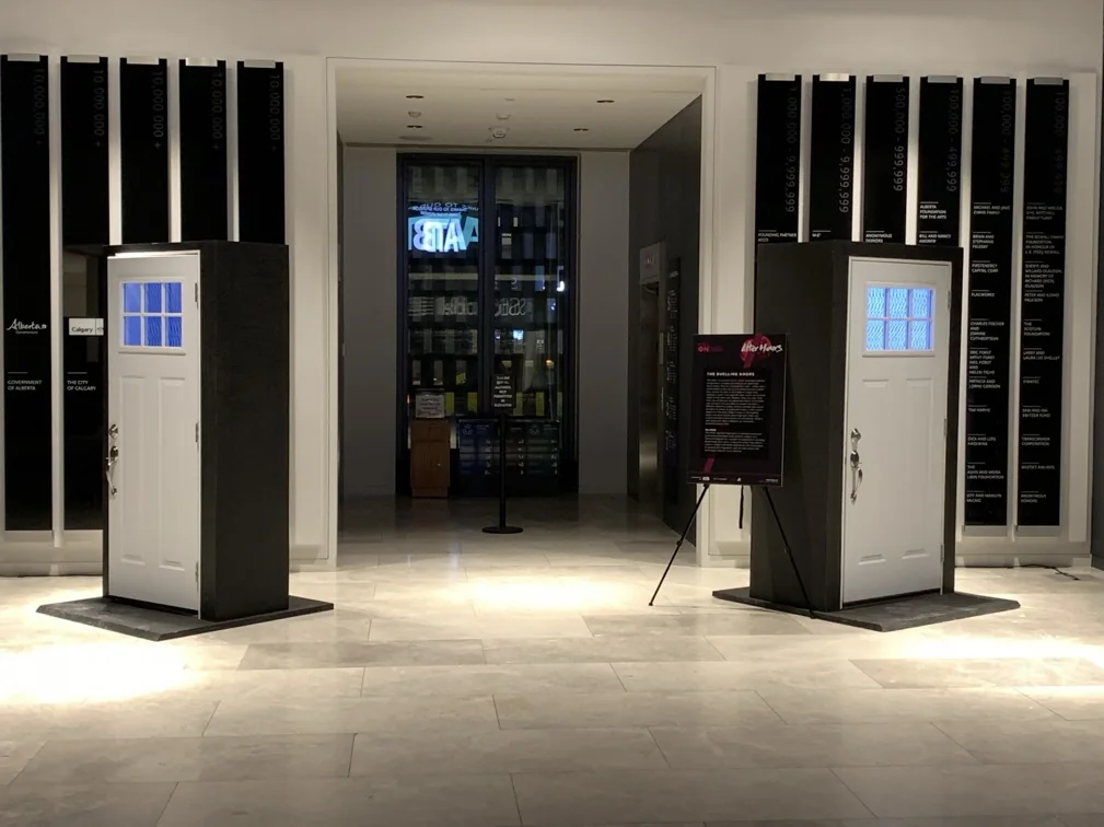 Two freestanding white doors with illuminated windows in The Doors installation.